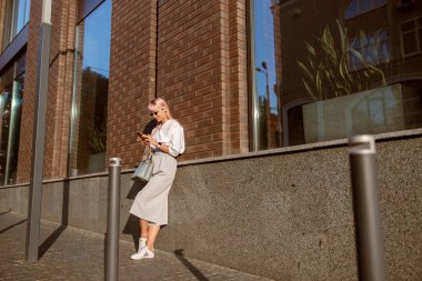 Sokakta cep telefonu kullanan genç bir kadın.