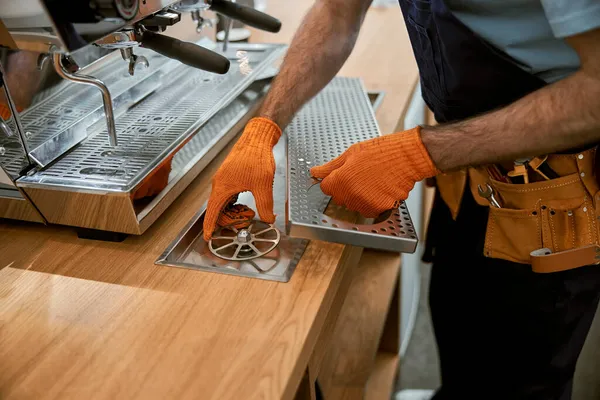 Mains masculines dans les gants de travail réparer la machine à café — Photo