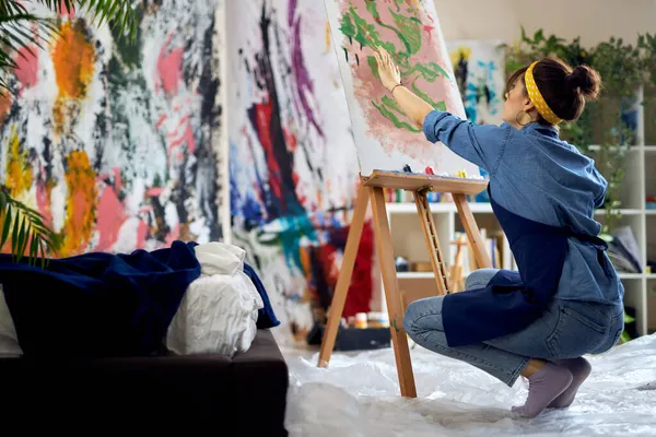 Mujer inspirada, artista femenina en delantal creando pintura abstracta en el taller de estudio en casa — Foto de Stock