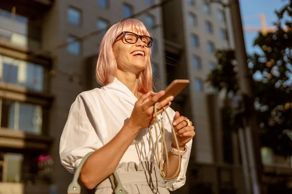Wanita ceria dengan ponsel berdiri di jalan — Stok Foto
