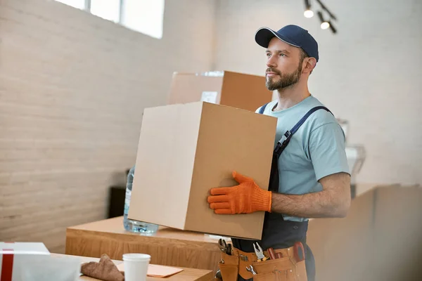 Бородатый молодой человек в перчатках держит картонную коробку — стоковое фото
