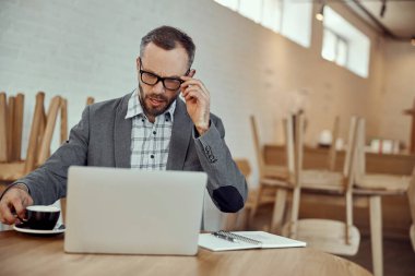 Kafede defter üzerinde çalışan sakallı adam.