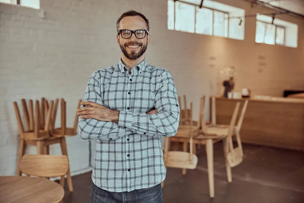 Cheerful bearded man in glasses standing in cafe — Stock Photo, Image