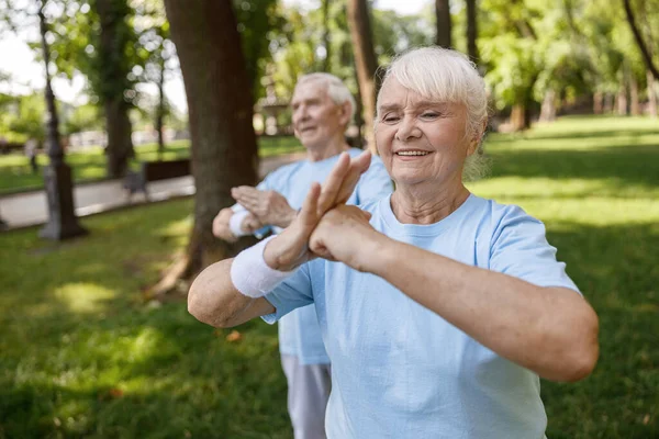 Lächelnde ältere Dame mit Partnerpraxis Chikung gemeinsam im grünen Stadtpark — Stockfoto