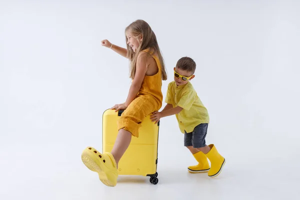 Чарівний маленький хлопчик дає сестрі їздити на проїзній валізі — стокове фото