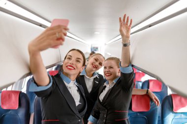 Neşeli hostesler uçakta selfie çekiyorlar.