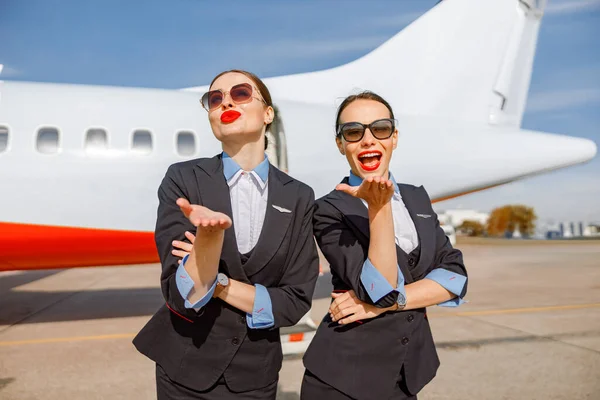Veselé ženy letušky posílají kuřbu polibek na letiště — Stock fotografie