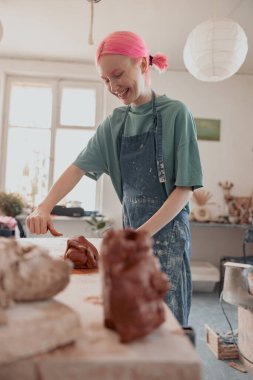 Çalışma odasında kille çalışan mutlu kadın çömlekçi.