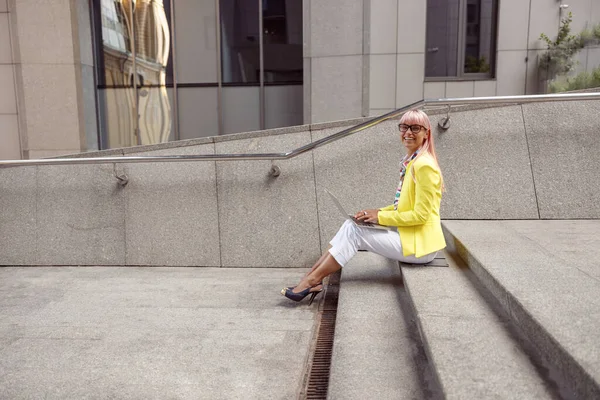 Lady on stairs smiling to camera during work with laptop — Stock Photo, Image