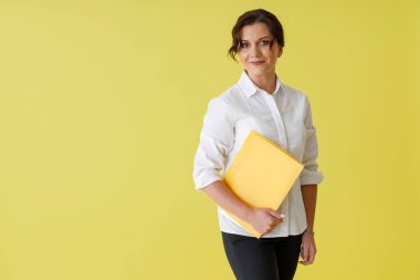 Belgeleri olan güzel bir kadın stüdyoda duruyor.