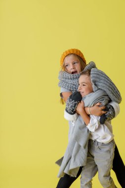 Örgü şapkalı şirin çocuklar stüdyoda sarılıyorlar.