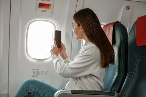 Viajera tomando fotos con teléfono móvil en aviones — Foto de Stock