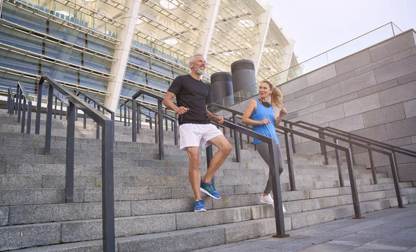 Mature couple, man and woman in sportswear making a workout session together, exercising on staircase outdoors — Fotografia de Stock
