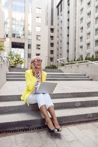 Wanita yang gembira memiliki panggilan selama bekerja di luar ruangan dengan laptop — Stok Foto
