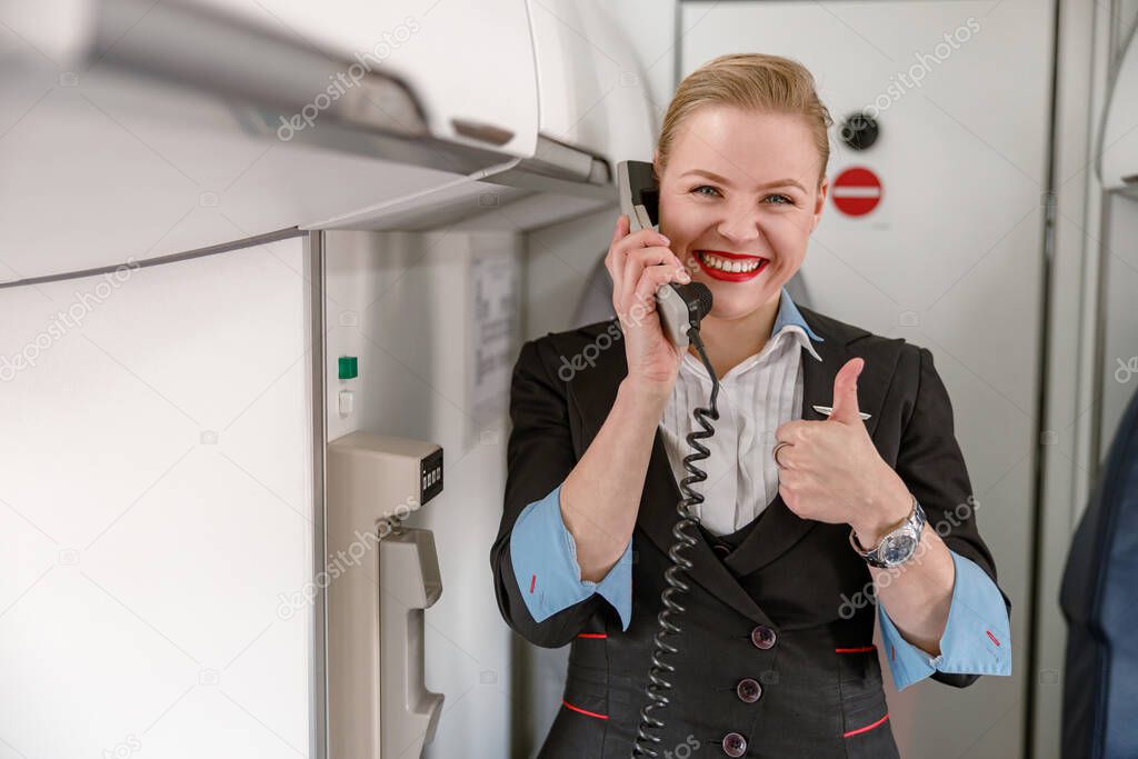 Joyful stewardess talking on telephone and giving thumbs up