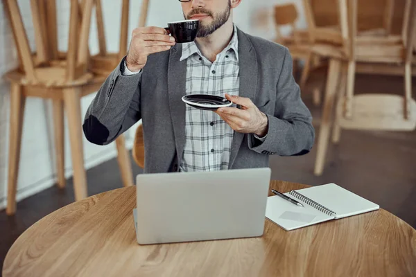 Anak muda minum kopi dan menggunakan notebook di kafe — Stok Foto