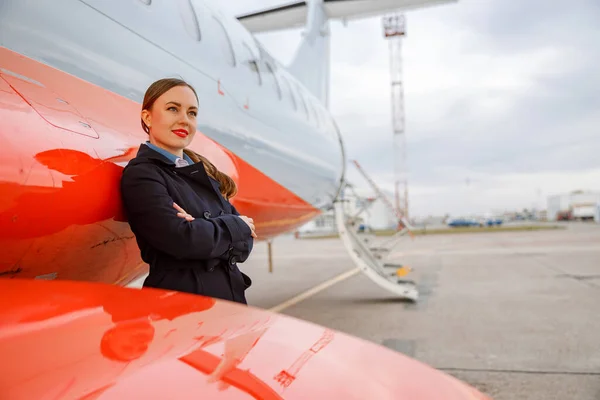 Mladá žena stojící v blízkosti soukromých letadel na letišti — Stock fotografie