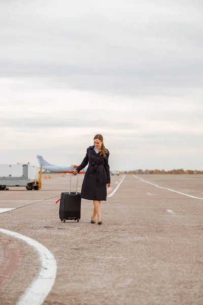 Wesoła kobieta z walizką podróżną stojąca na zewnątrz na lotnisku — Zdjęcie stockowe