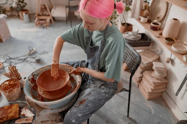 Young potter shaping clay with instrument in art studio — Stockfoto