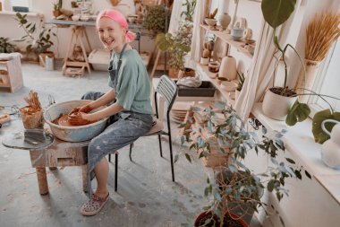 Potter, çalışma odasındaki çömlek çarkında elle çalışıyor.