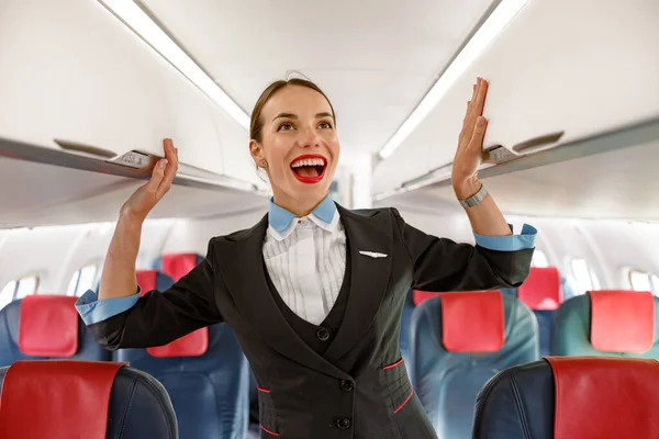 Joyful stewardess standing in airplane passenger salon — Stock fotografie