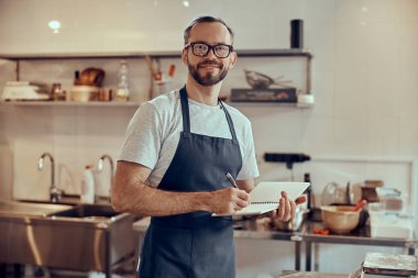 Kafede deftere yazan neşeli erkek işçi.