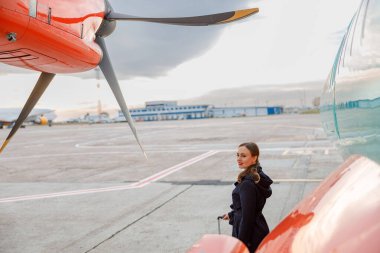 Joyful woman standing near airplane at airport