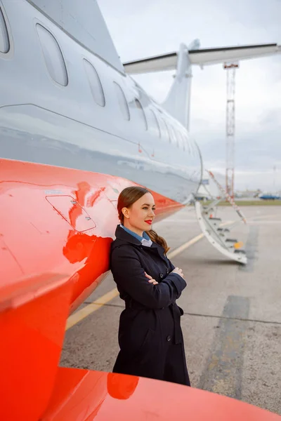 Young woman standing near passenger airplane at airport — Stock fotografie