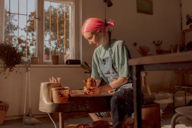 Genç bayan usta çömlek odasında kille çalışıyor.