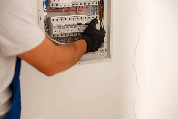 Hand eines Elektrotechnikers überprüft Sicherungen in einem Schaltschrank an der Wand — Stockfoto