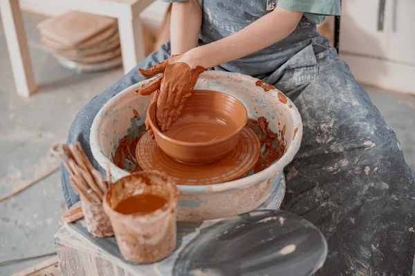 Jonge vrouw werkt op aardewerk wiel in atelier — Stockfoto