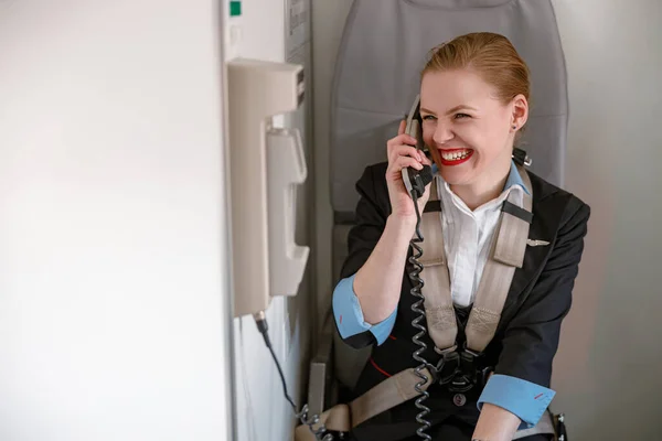 Alegre azafata hablando por teléfono en cabina de avión —  Fotos de Stock