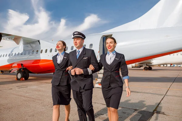 Piloto de aviones y azafatas caminando por el aeródromo — Foto de Stock