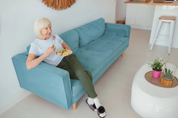 Goed uitziende oude vrouw eet thuis eten binnen — Stockfoto