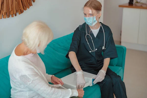 Especialista en salud revisando paciente anciano en casa — Foto de Stock