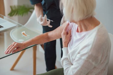 Yaşlı kadın evinde aşı oluyor.