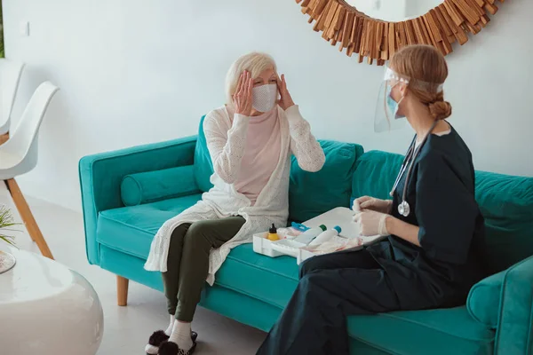 Verpleegster controleert de gezondheid van oudere vrouw in de woonkamer — Stockfoto