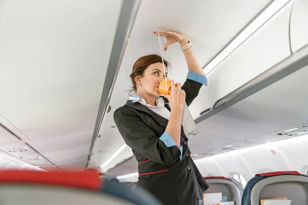 Asistente de vuelo demostrando cómo utilizar la máscara de oxígeno en el avión — Foto de Stock