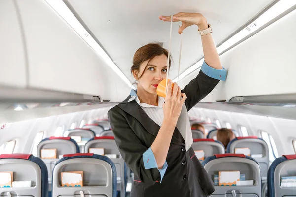Female stewardess demonstrating how to use oxygen mask in plane — Stock Photo, Image