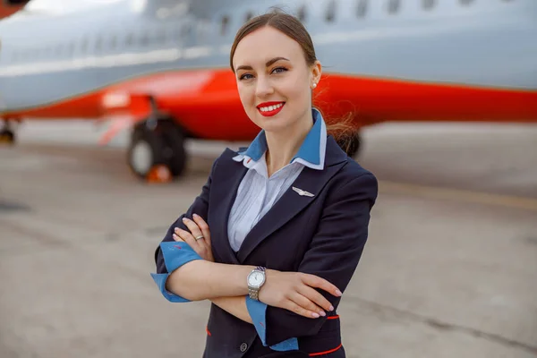 Asistente de vuelo femenina alegre de pie al aire libre en el aeropuerto — Foto de Stock