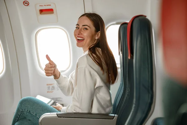 Joven alegre haciendo el gesto de los pulgares hacia arriba en el avión — Foto de Stock