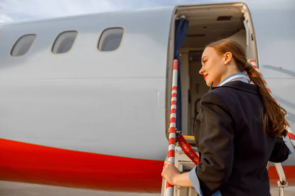 Žena letuška stojící na schodech letadla — Stock fotografie