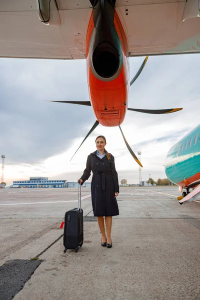 Radostná žena s cestovní taškou stojící pod vrtulí — Stock fotografie
