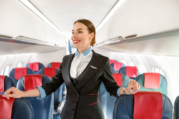 Asistente de vuelo alegre mujer de pie en el salón de pasajeros de aviones — Foto de Stock