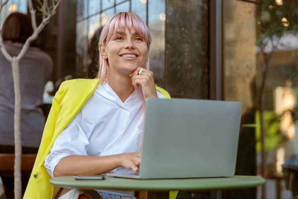 Wanita ceria bekerja pada laptop di kafe outdoor — Stok Foto