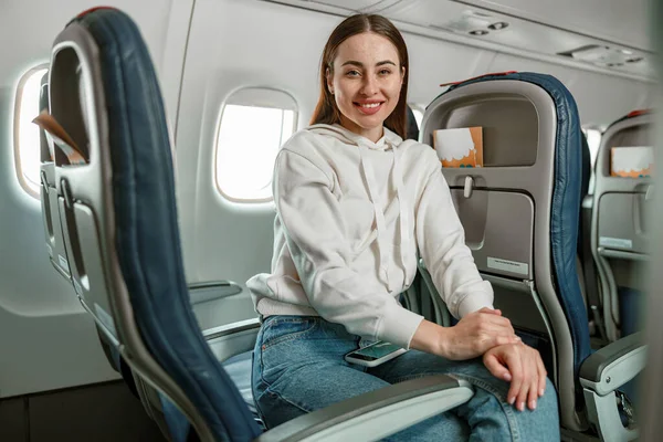Jovencita alegre sentada en silla de pasajeros en avión — Foto de Stock