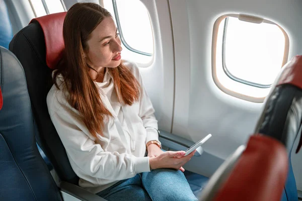 Молода жінка використовує мобільний телефон у літаку — стокове фото
