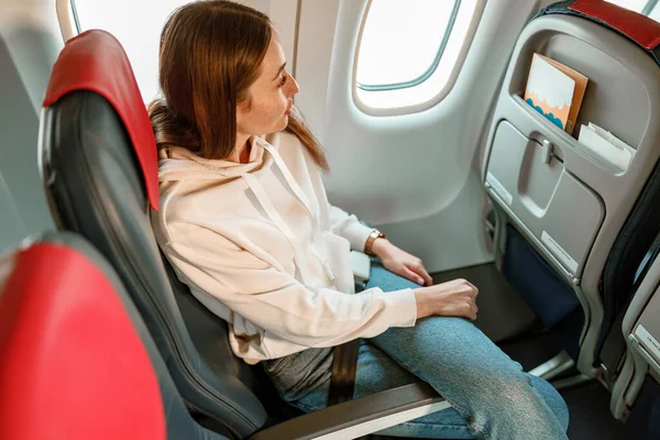 Mujer joven sentada en silla de pasajeros en avión — Foto de Stock