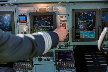 Pilot uçak kokpitinde kontrol panelini kullanıyor.