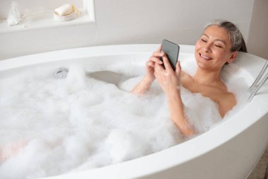 Güzel Asyalı kadın küvette yatıyor.